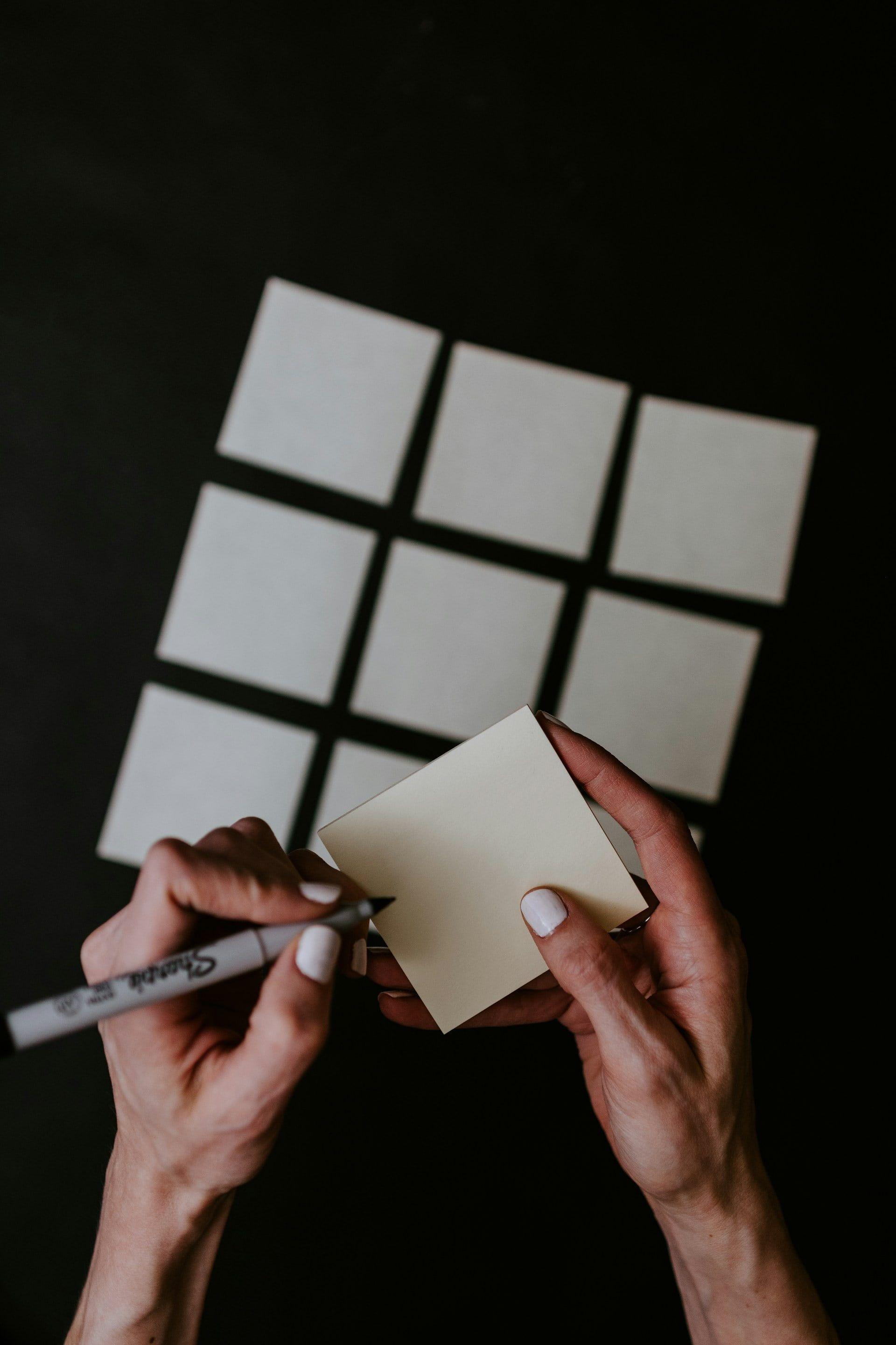 une main tenant une feuille de papier et un stylo