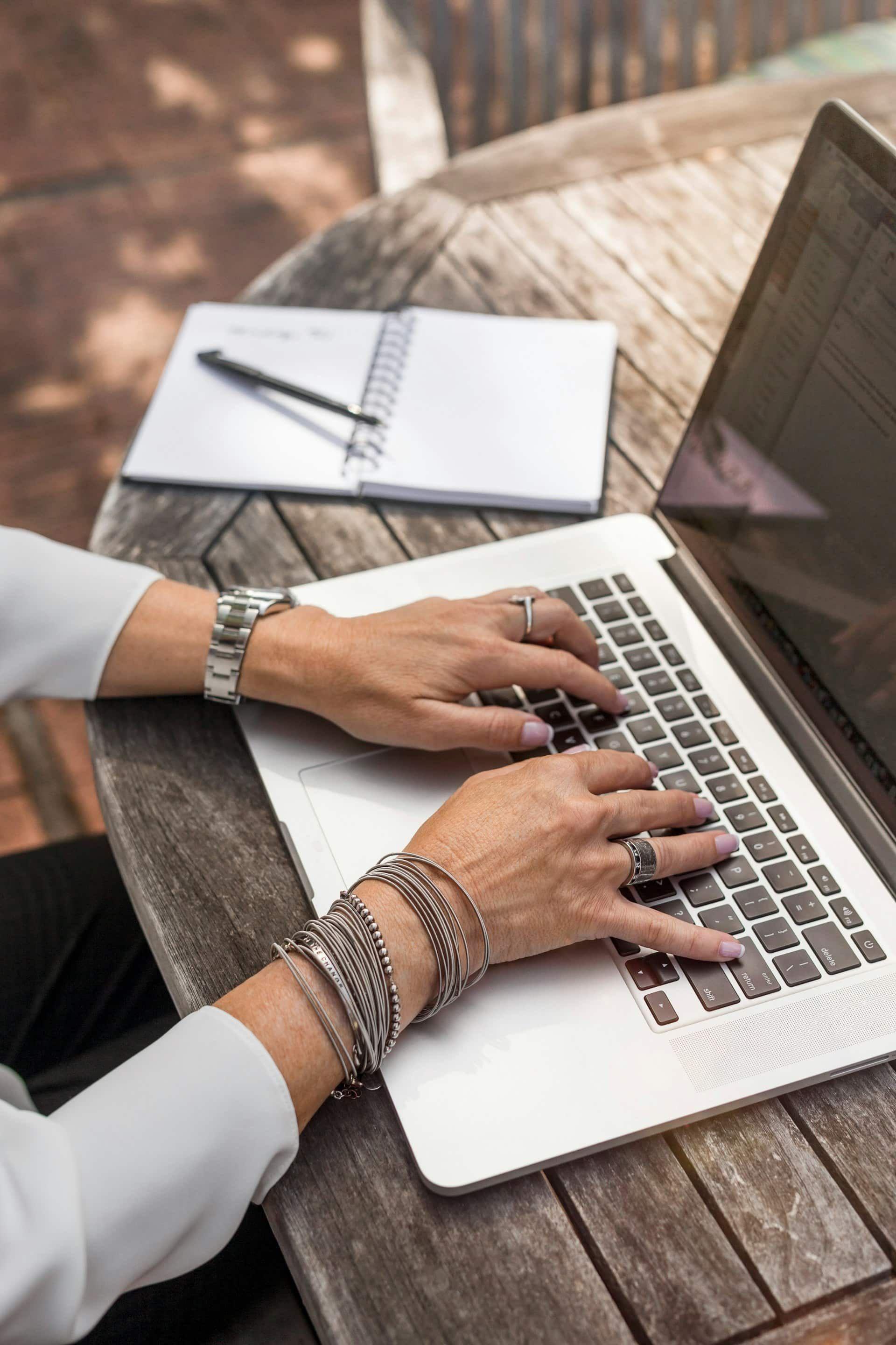 Uma mulher digitando em um laptop em uma mesa ao ar livre