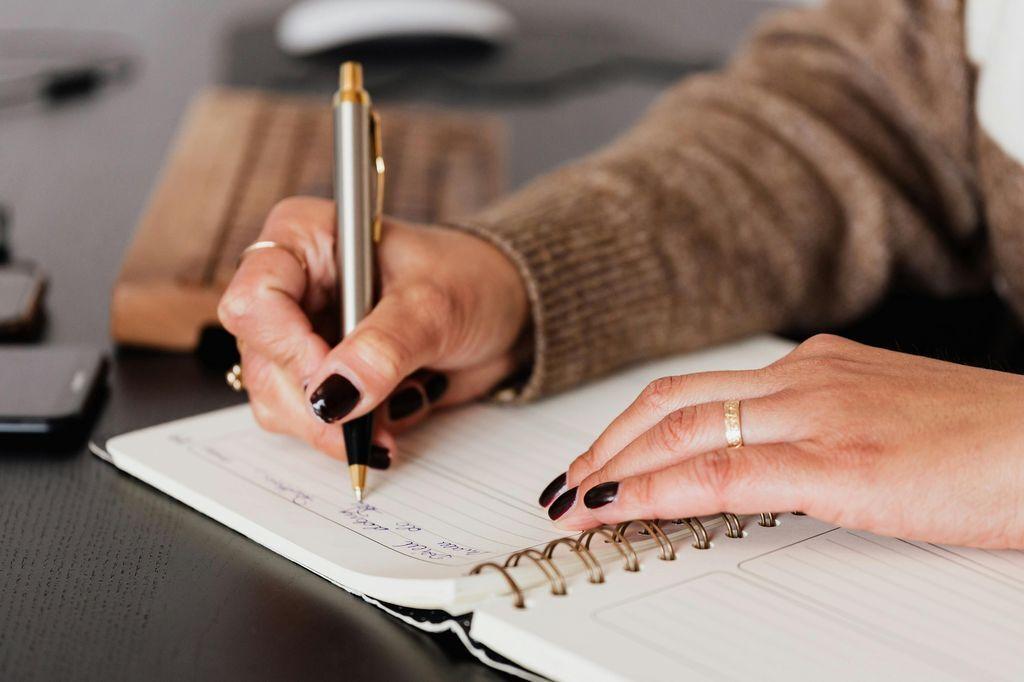 a woman writing in a notebook with a pen