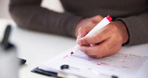 a person writing on a piece of paper with a pen