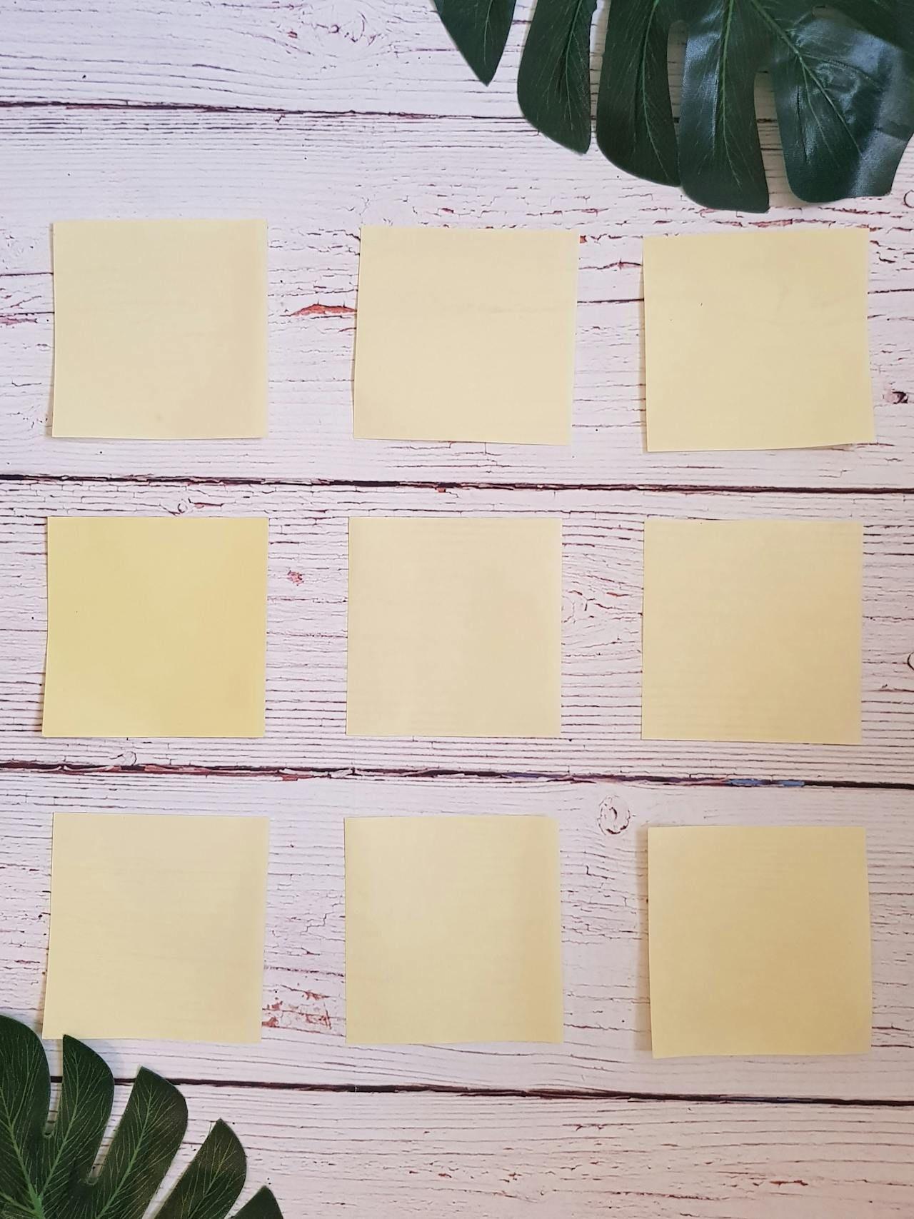 Rumeni post-it listki, razporejeni na beli leseni mizi.