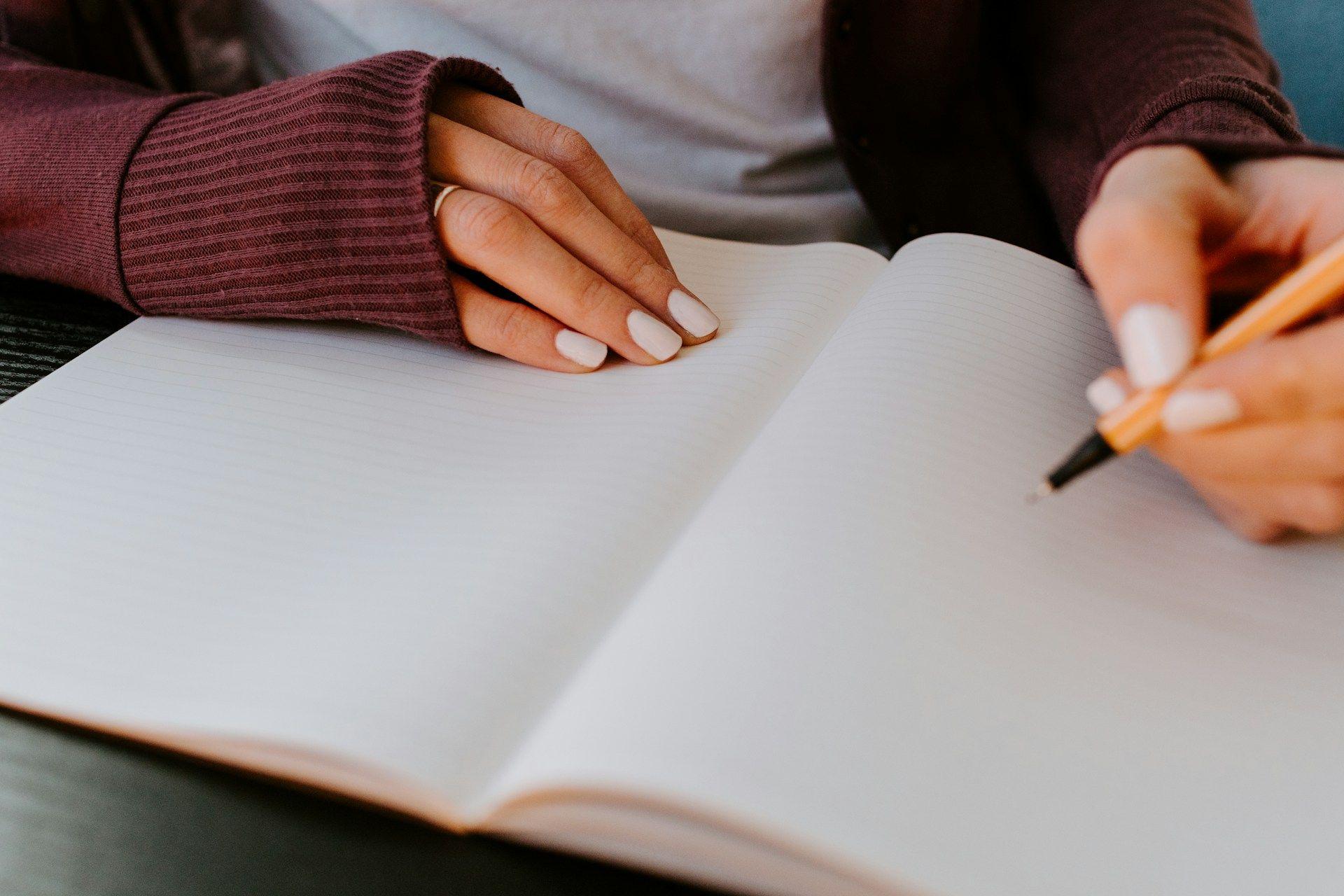 a woman writing in a notebook with a pen