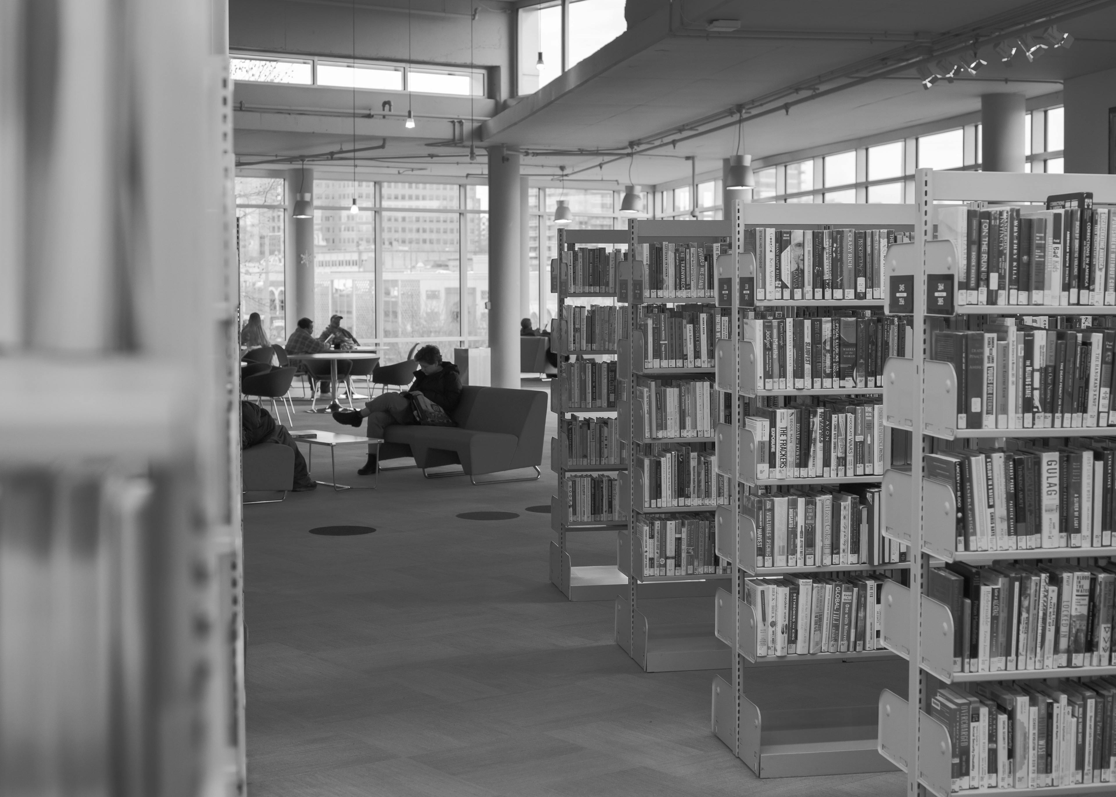 une bibliothèque remplie de nombreux livres et des personnes assises à des tables