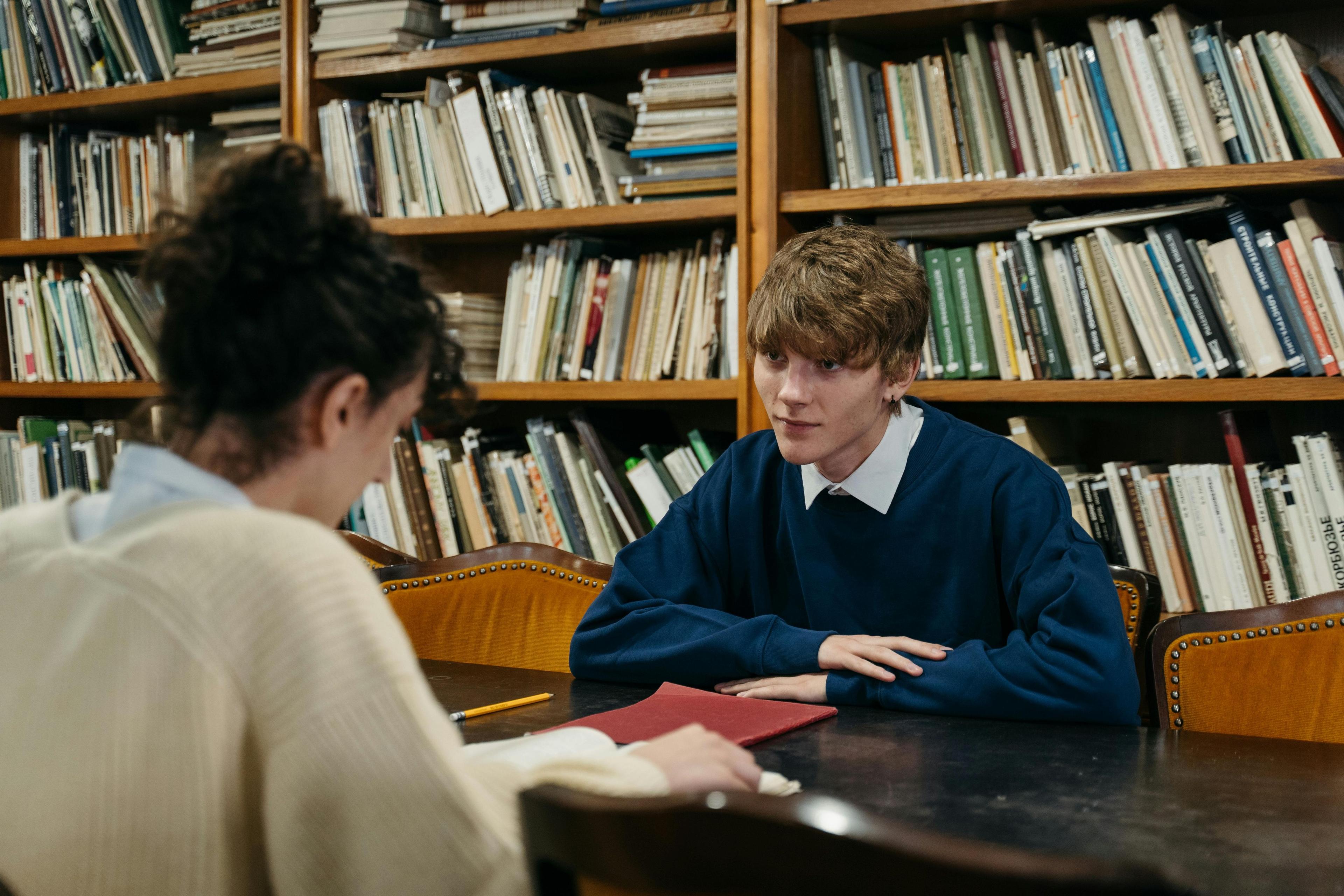 um homem e uma mulher sentados em uma mesa em uma biblioteca