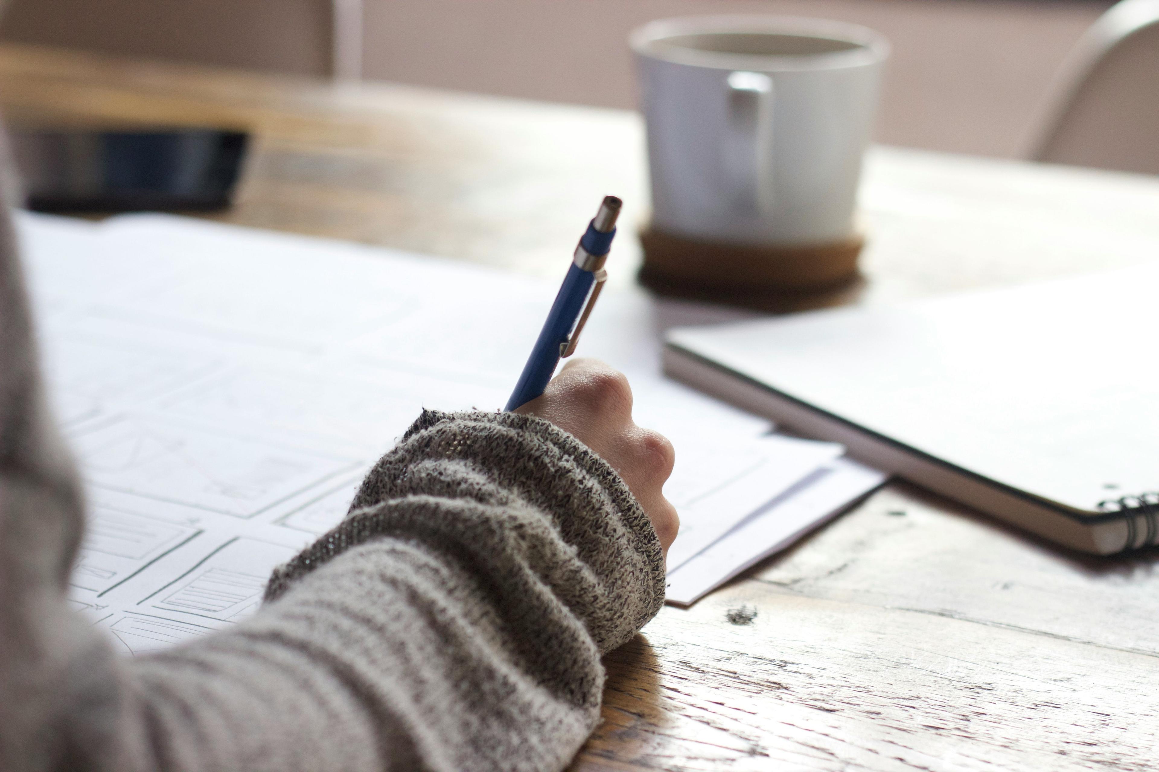 une personne assise à une table avec un stylo et du papier