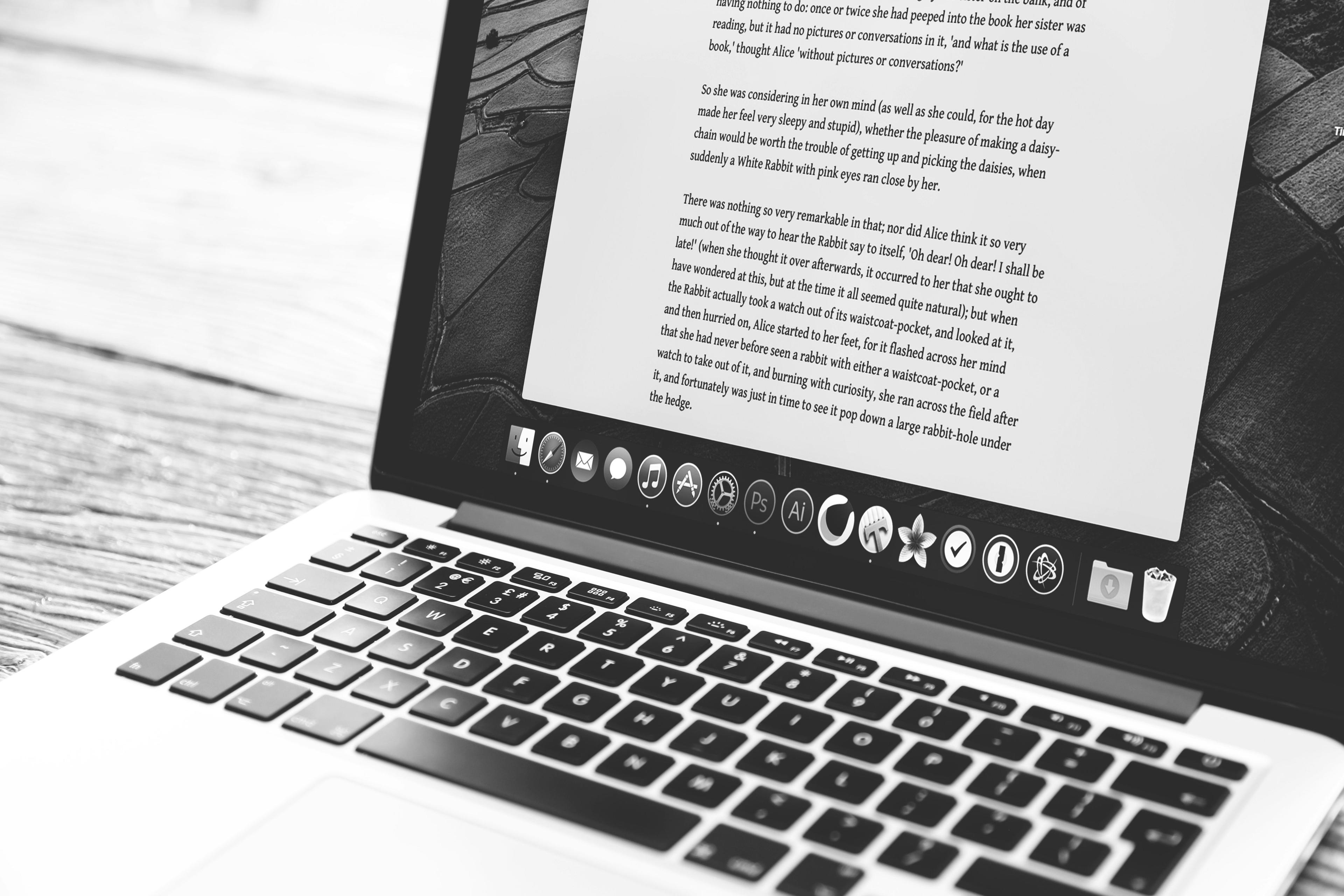 a laptop with a book on it on a wooden table