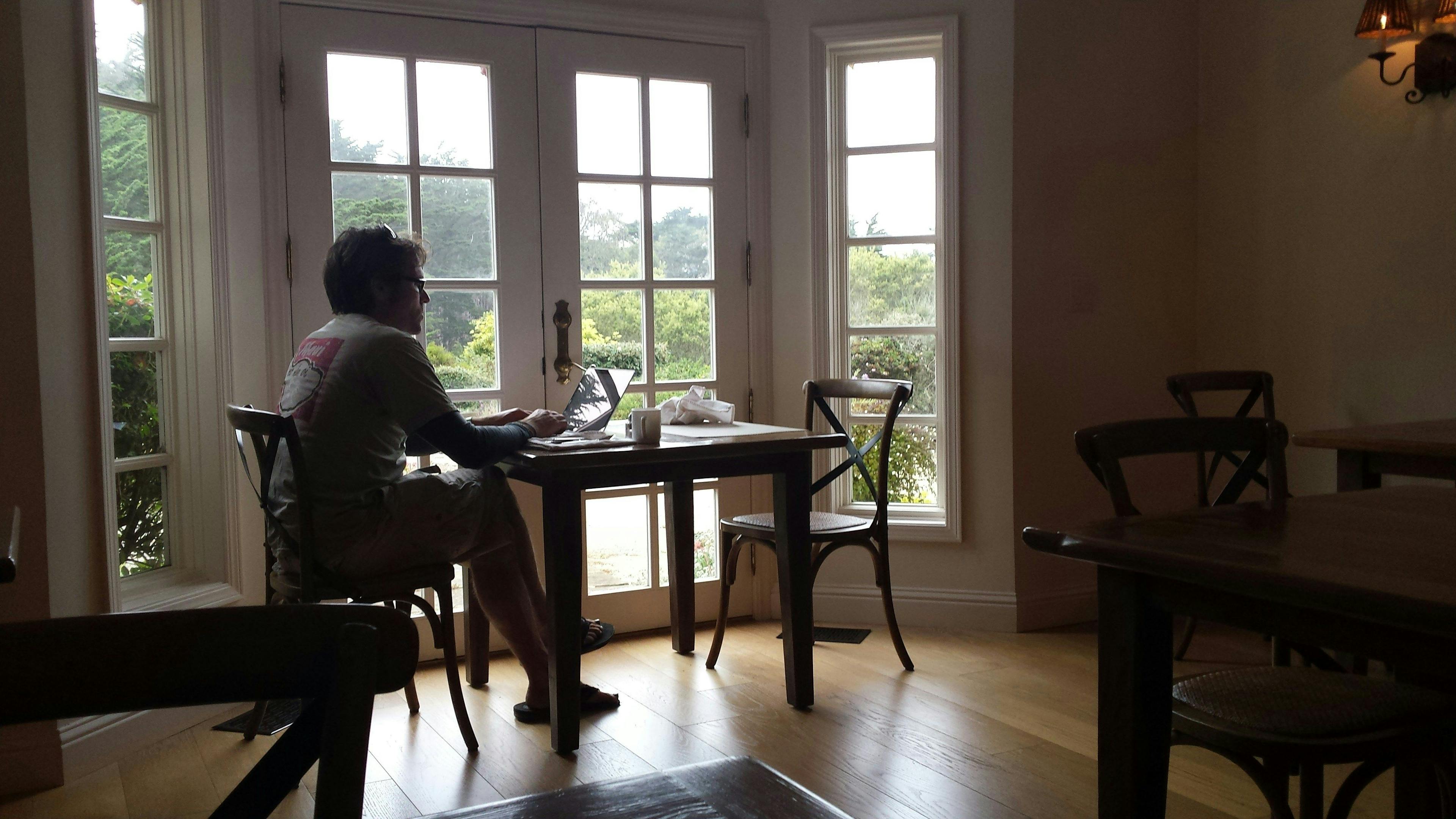 une femme assise à une table devant une fenêtre