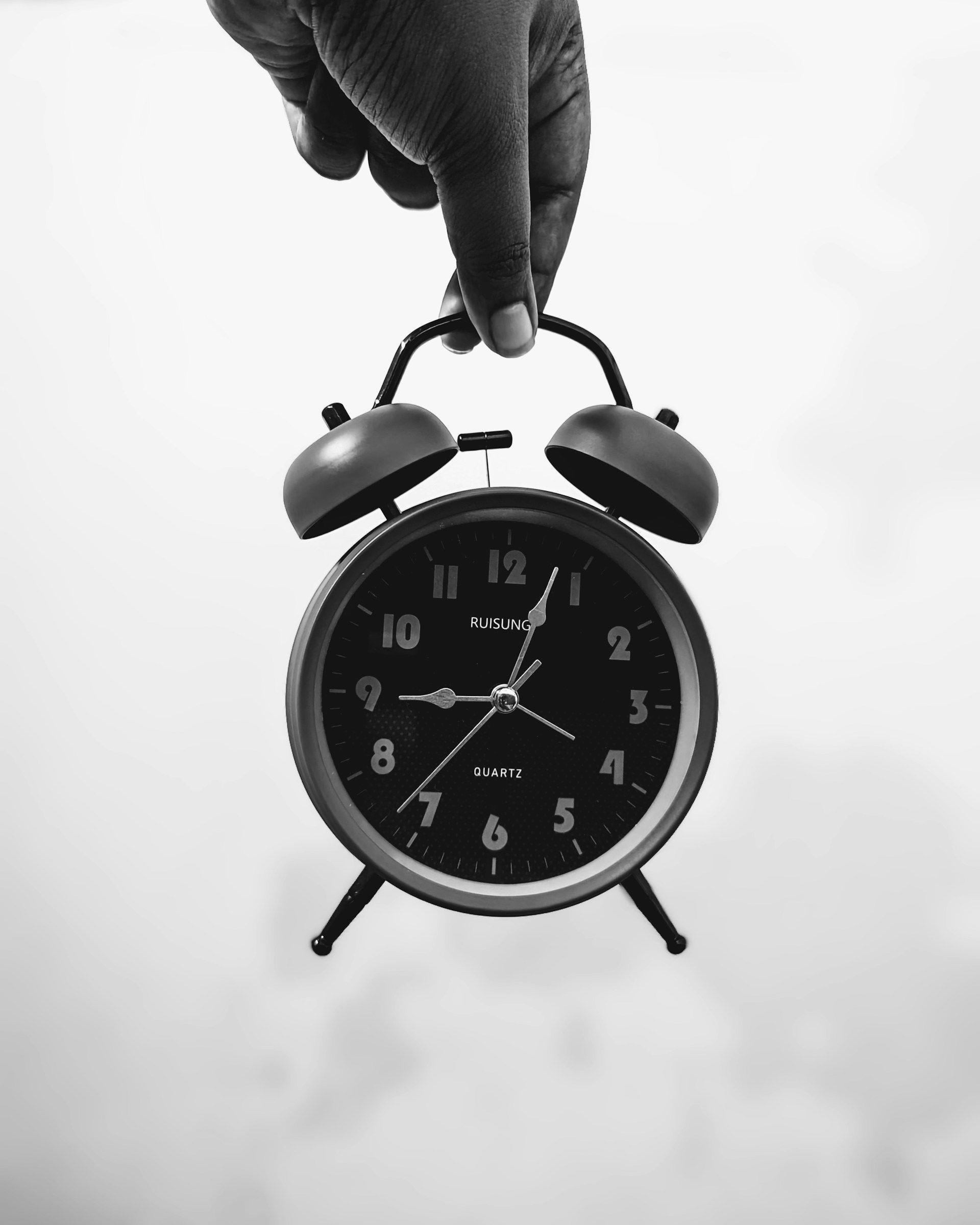 a person's hand holding an alarm clock