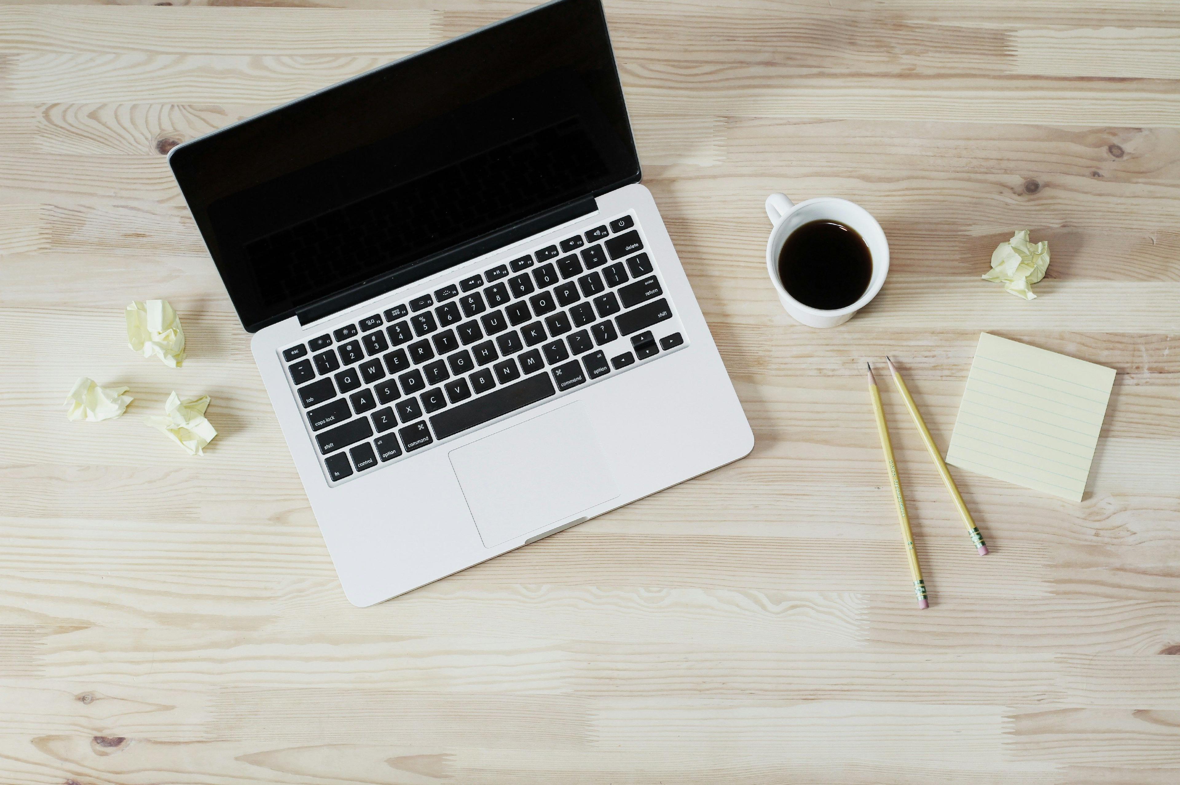 una laptop y una taza de café sobre una mesa de madera