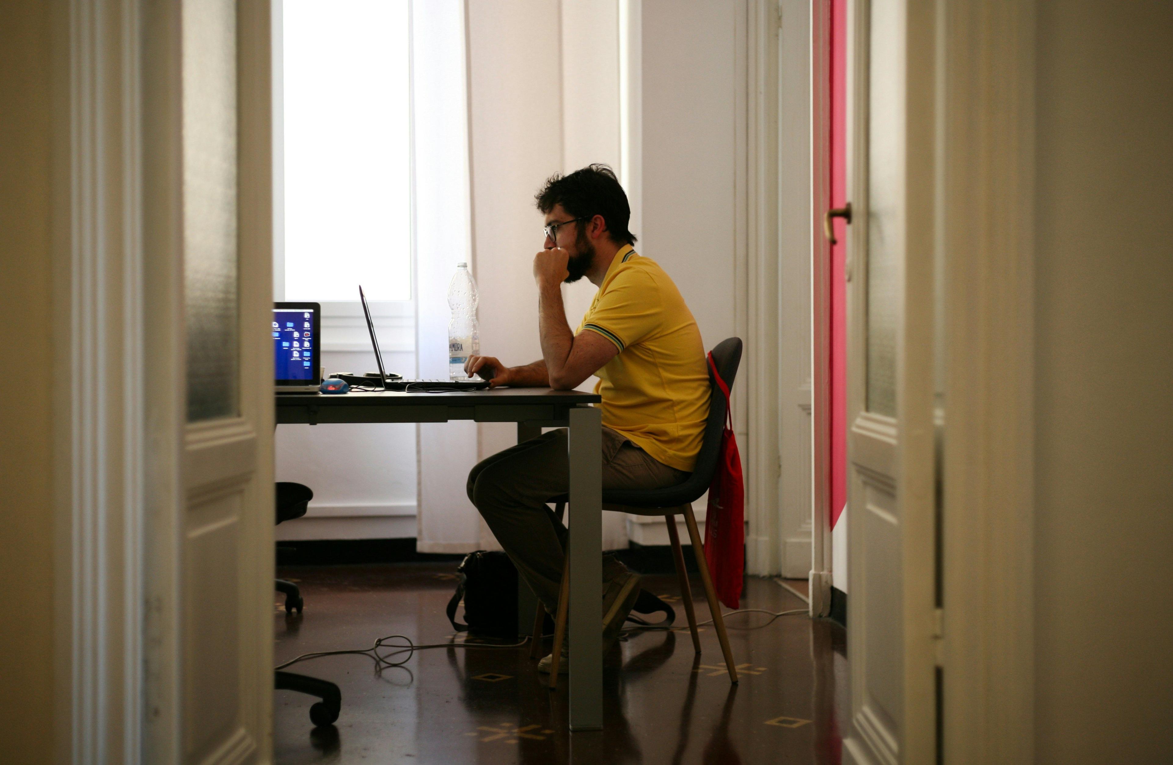 um homem sentado em uma mesa usando um laptop