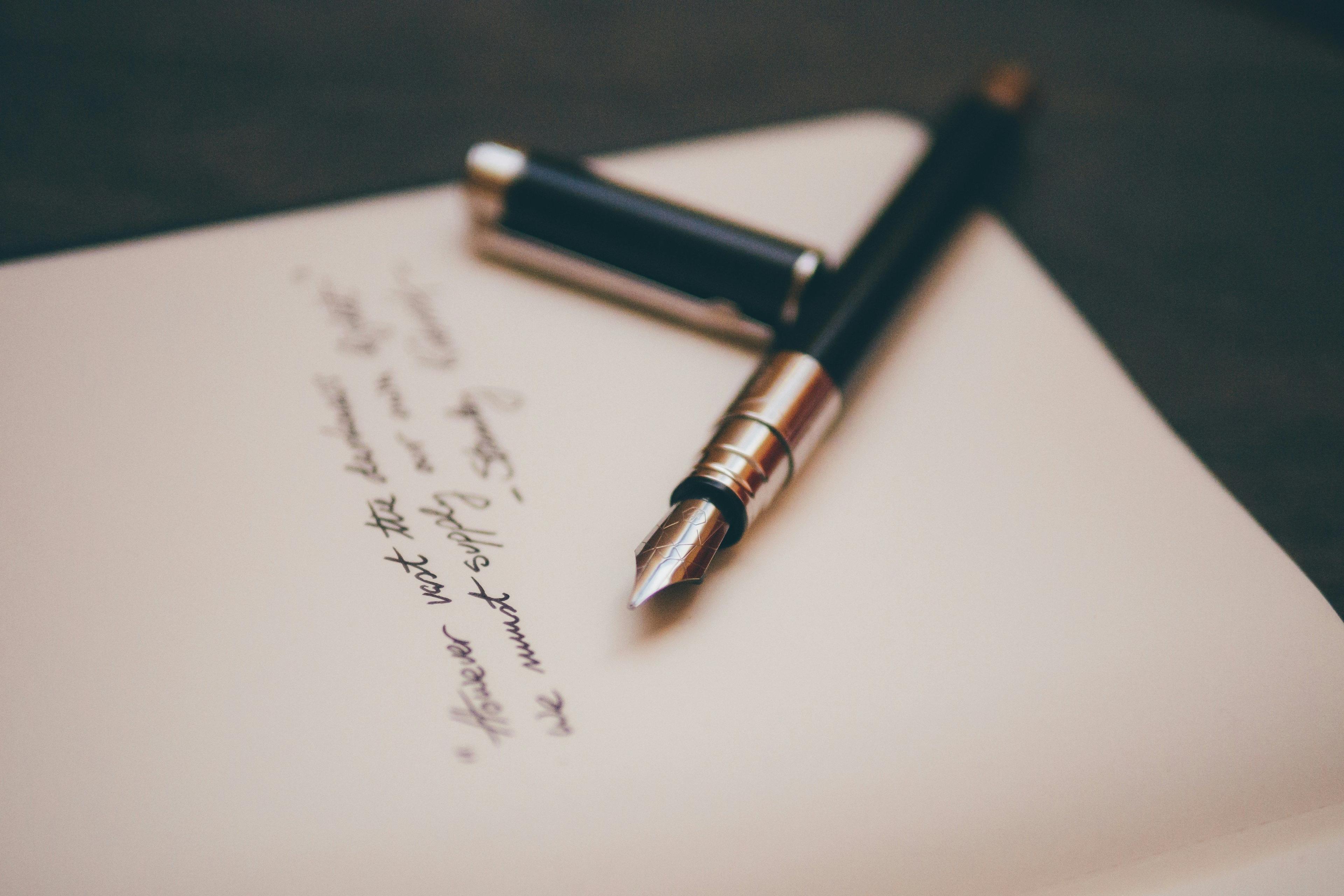 a fountain pen sits on top of an open notebook