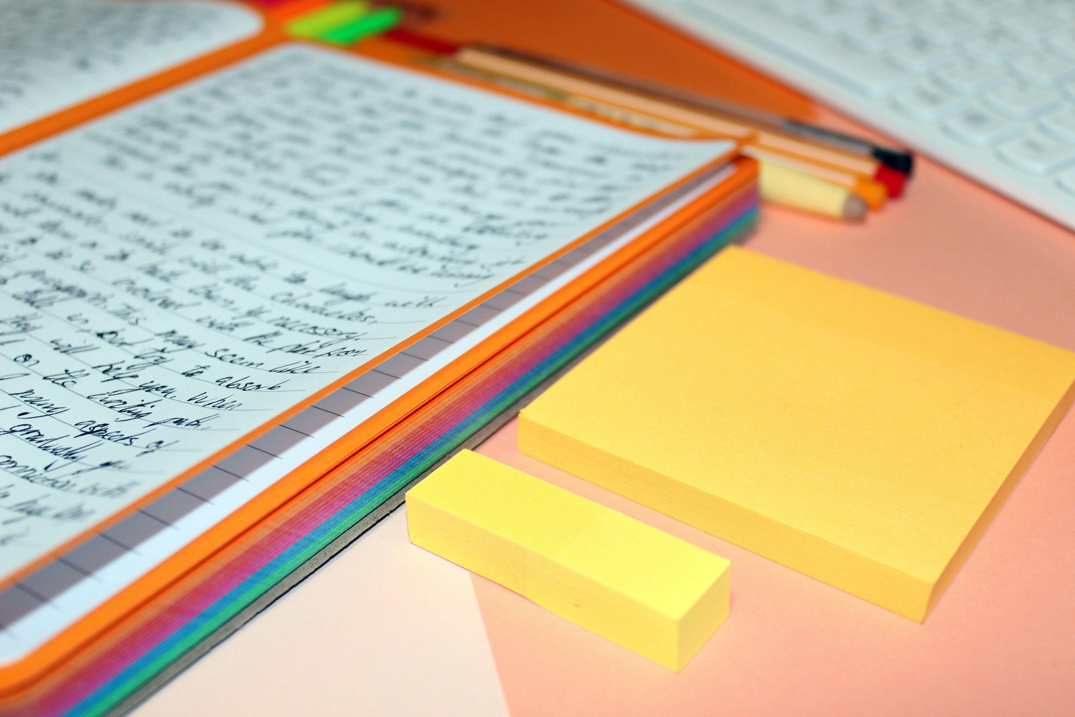 a notebook with sticky notes and a pencil