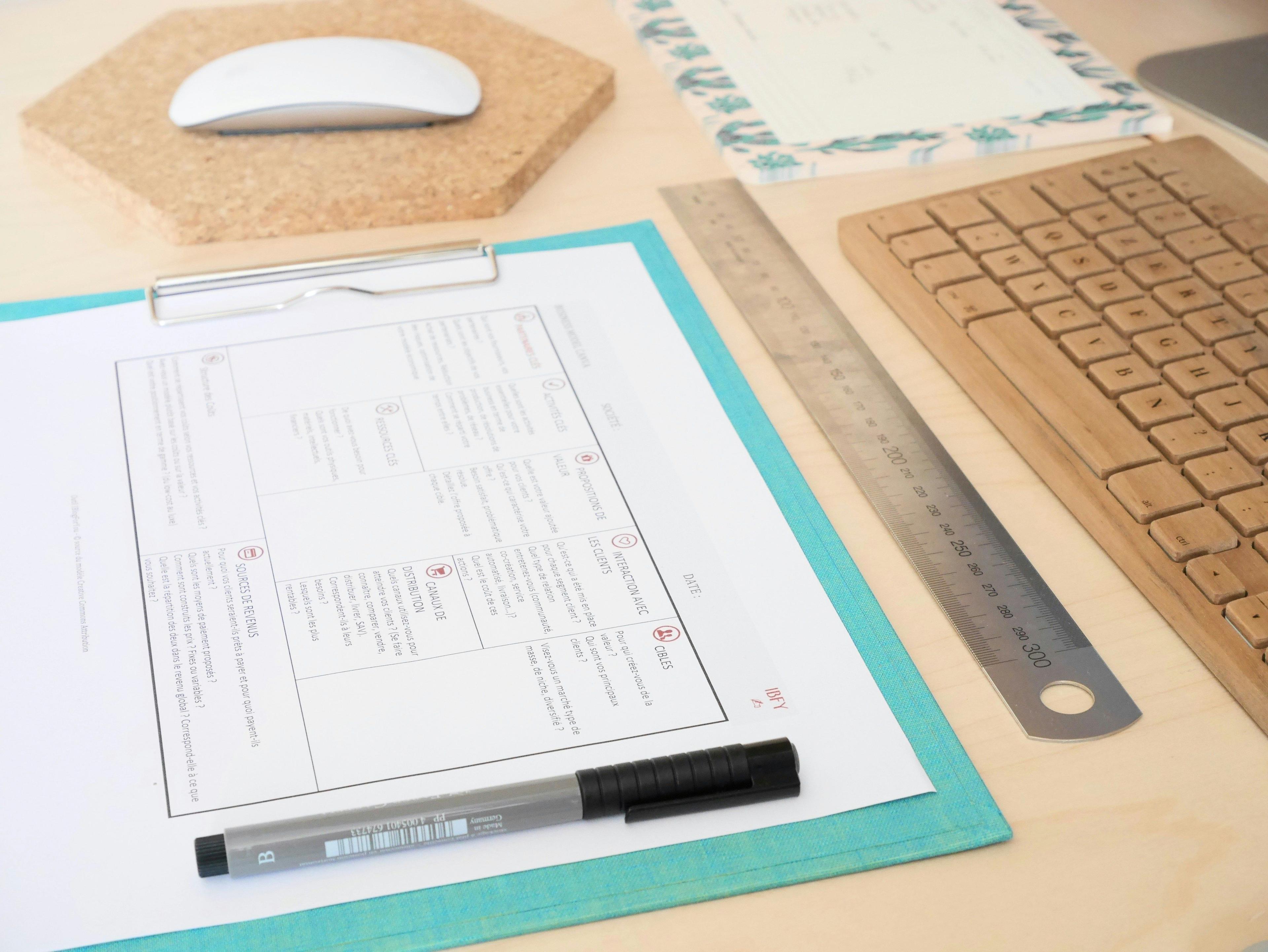 a desk with a keyboard, mouse and paper