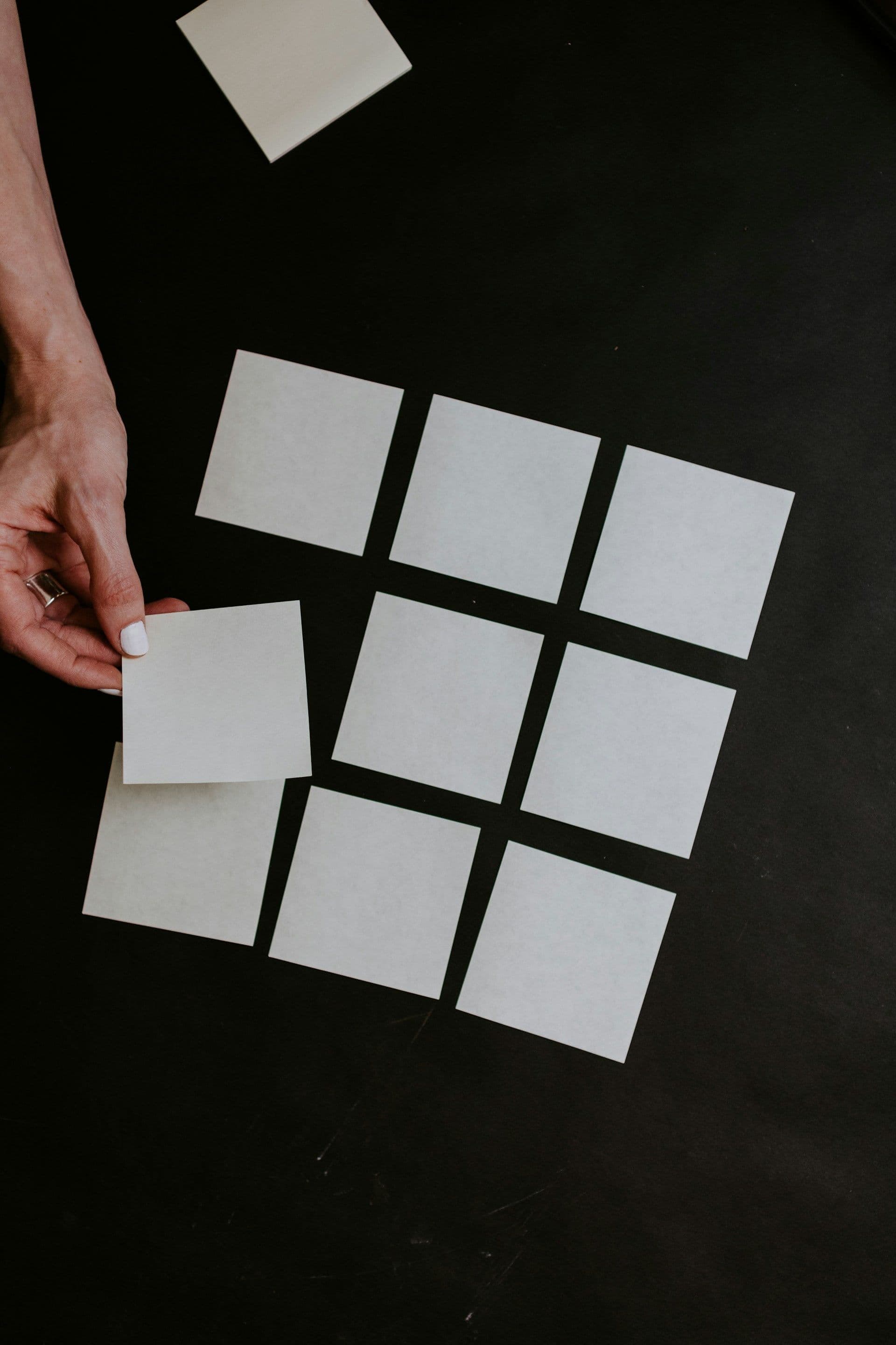 a person placing paper squares on a table