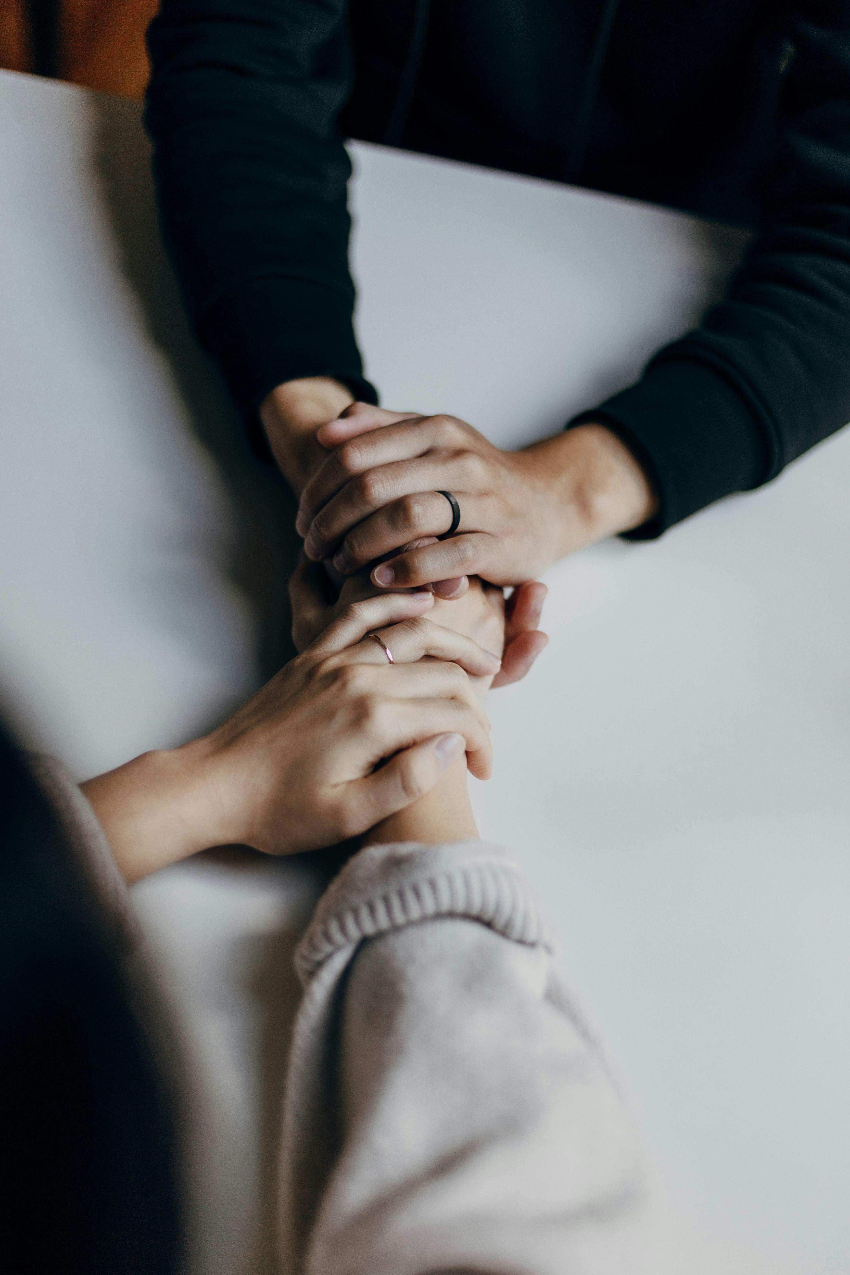 duas pessoas segurando as mãos sobre uma mesa