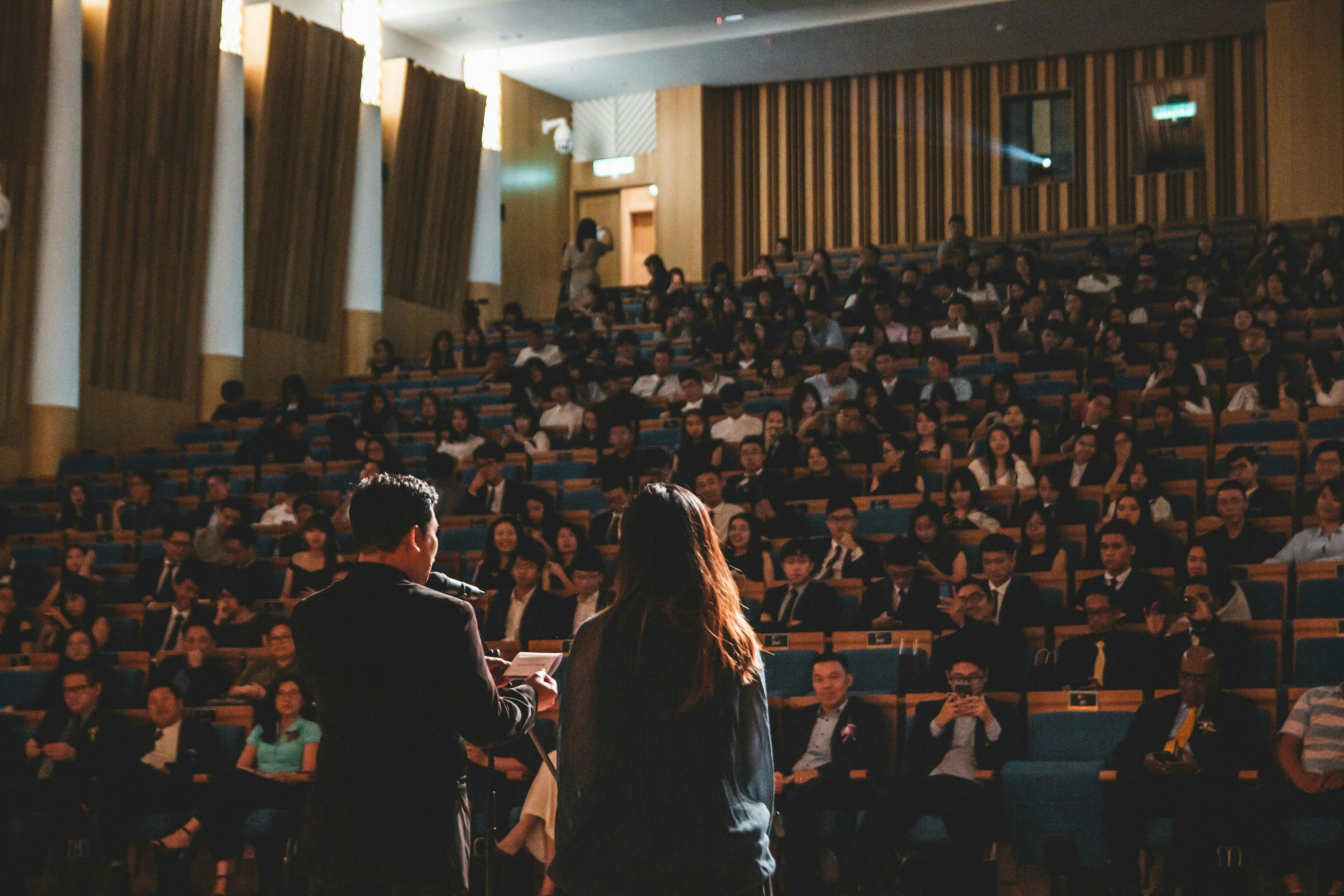 un homme et une femme debout devant un auditorium