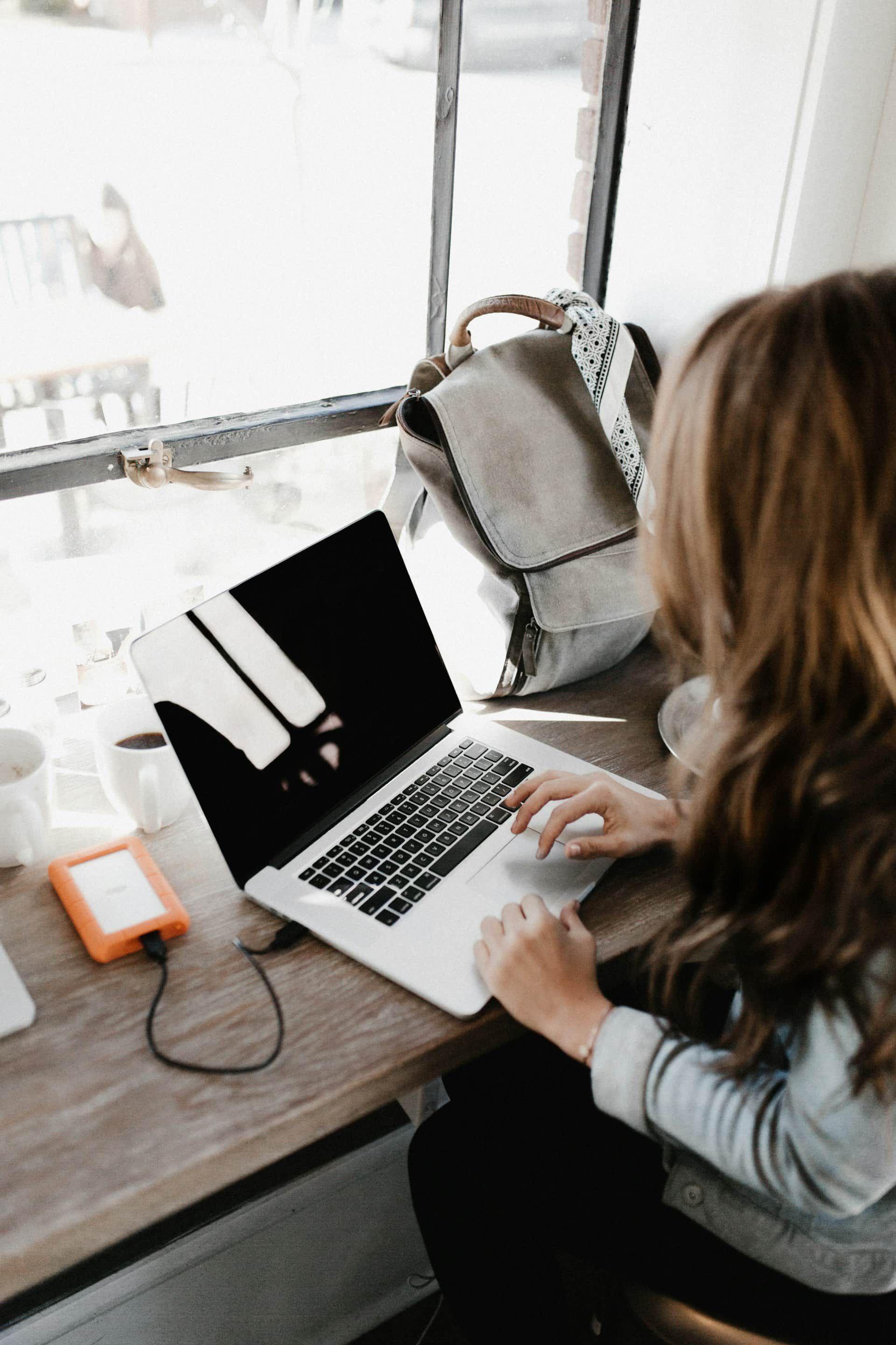 a woman working on a laptop in front of a window