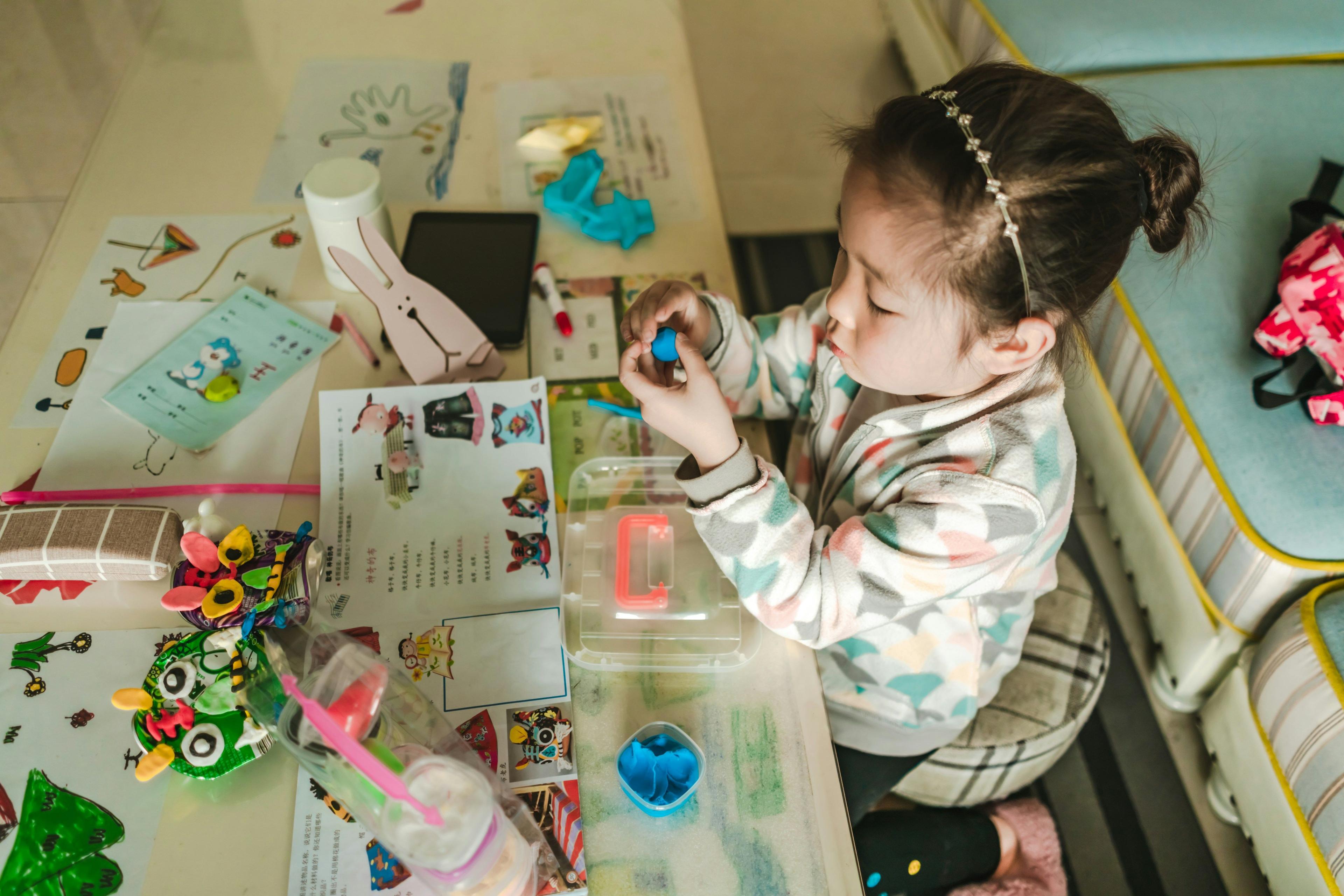 a little girl sitting at a table with toys