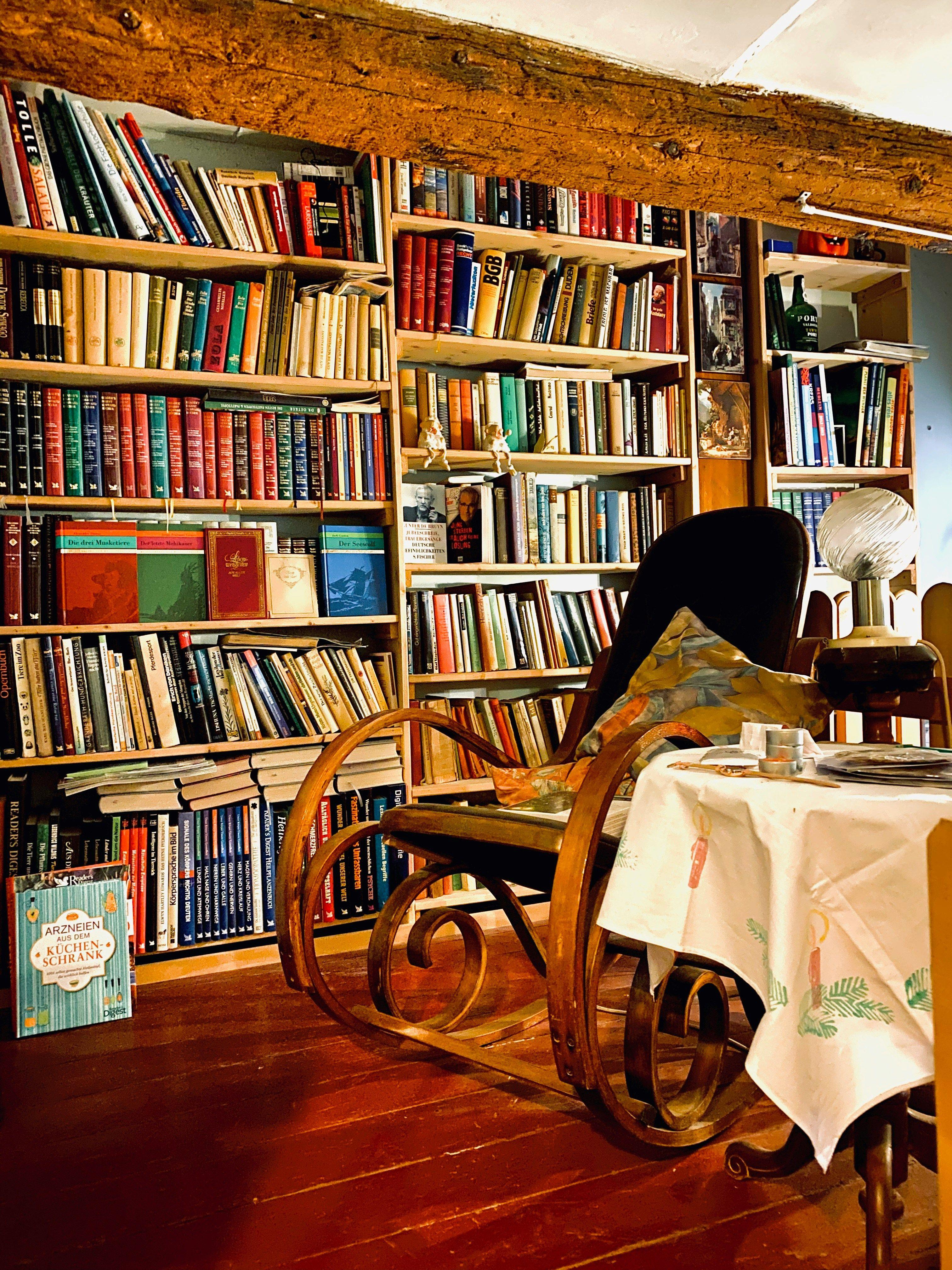 a room filled with lots of books and a rocking chair