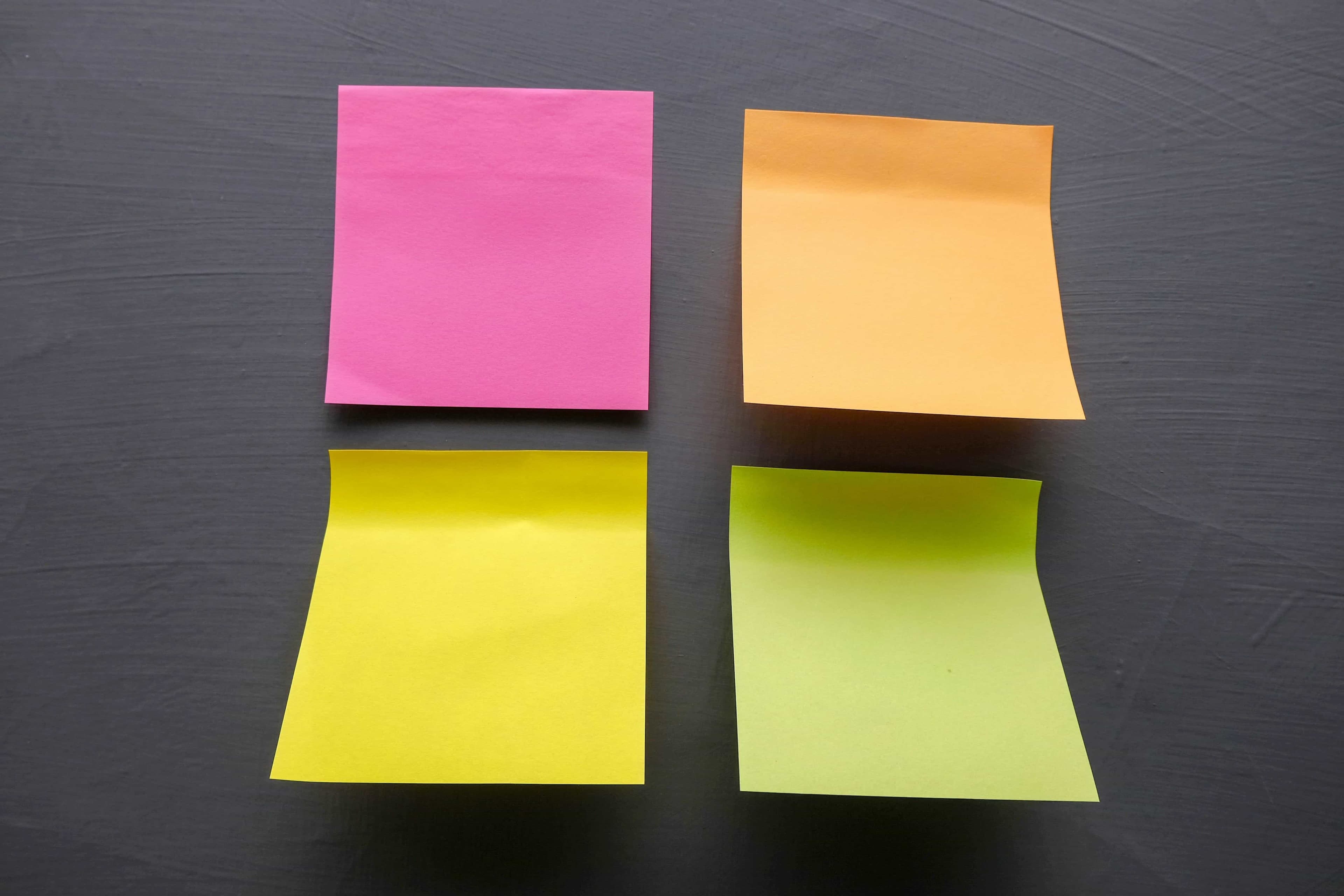 four colored sticky notes on a gray surface