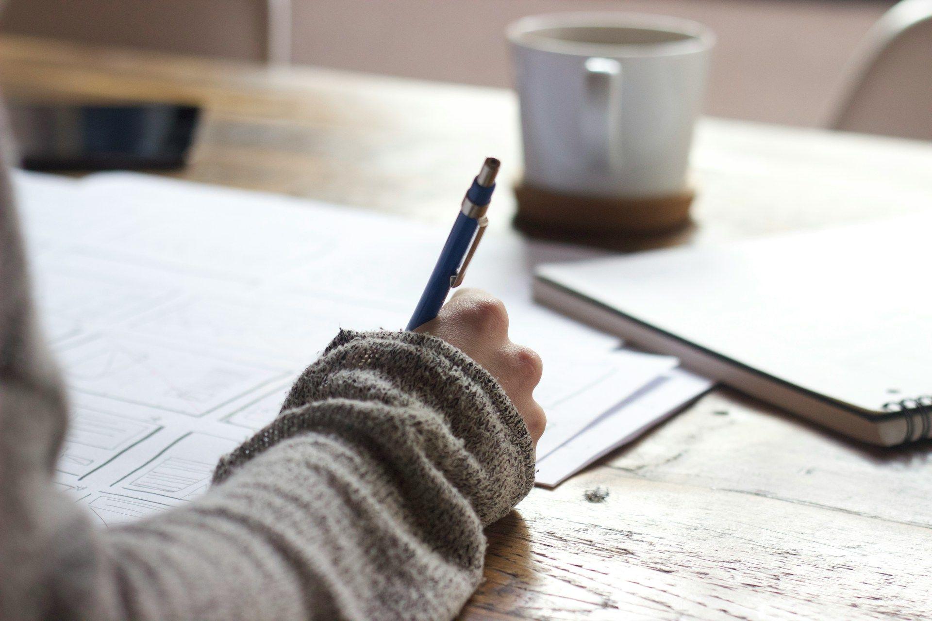 a person writing on a piece of paper with a pen