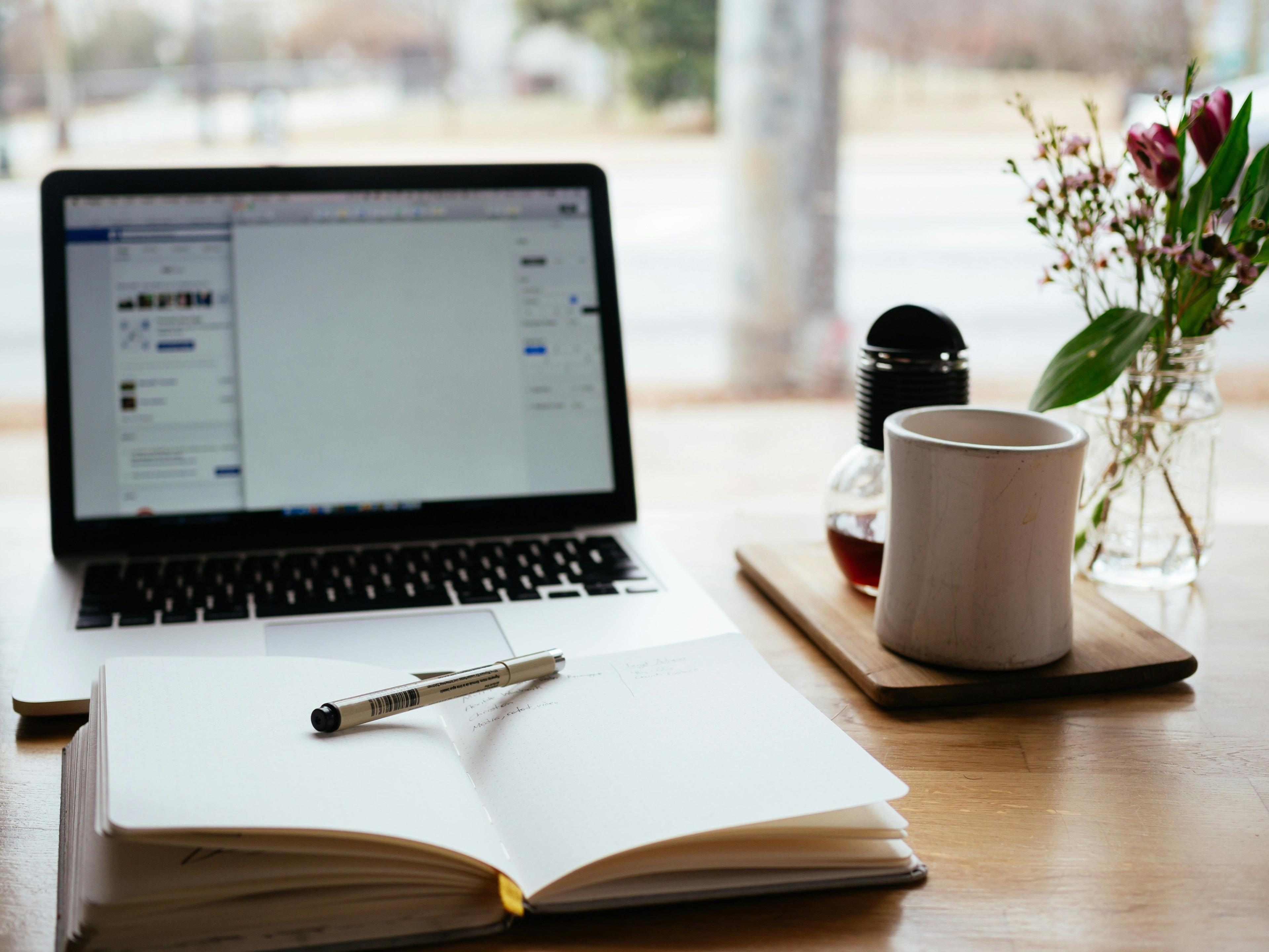 um laptop e um caderno sobre uma mesa de madeira