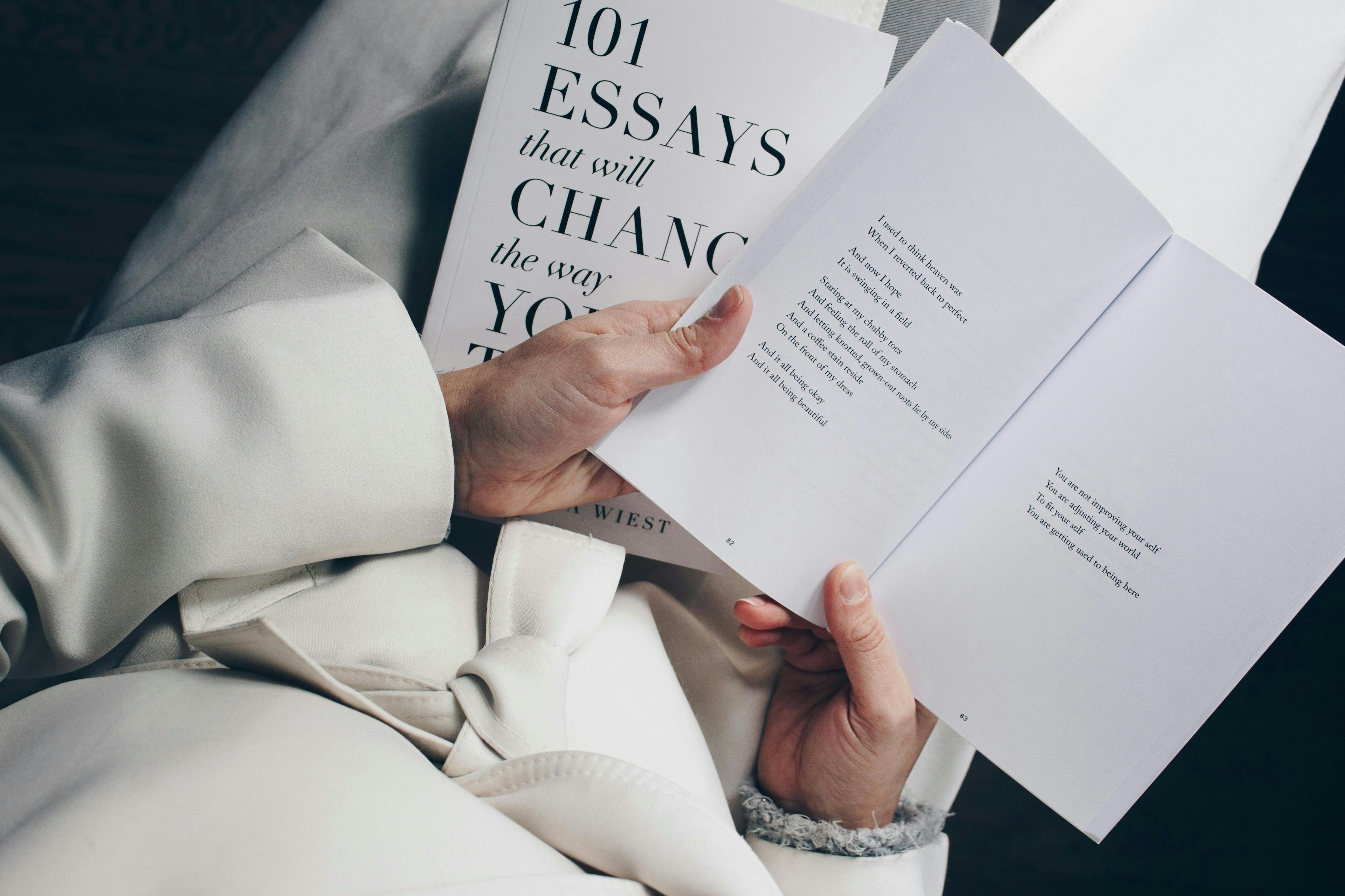 une femme tenant un livre intitulé 100 essais qui changeront votre vie