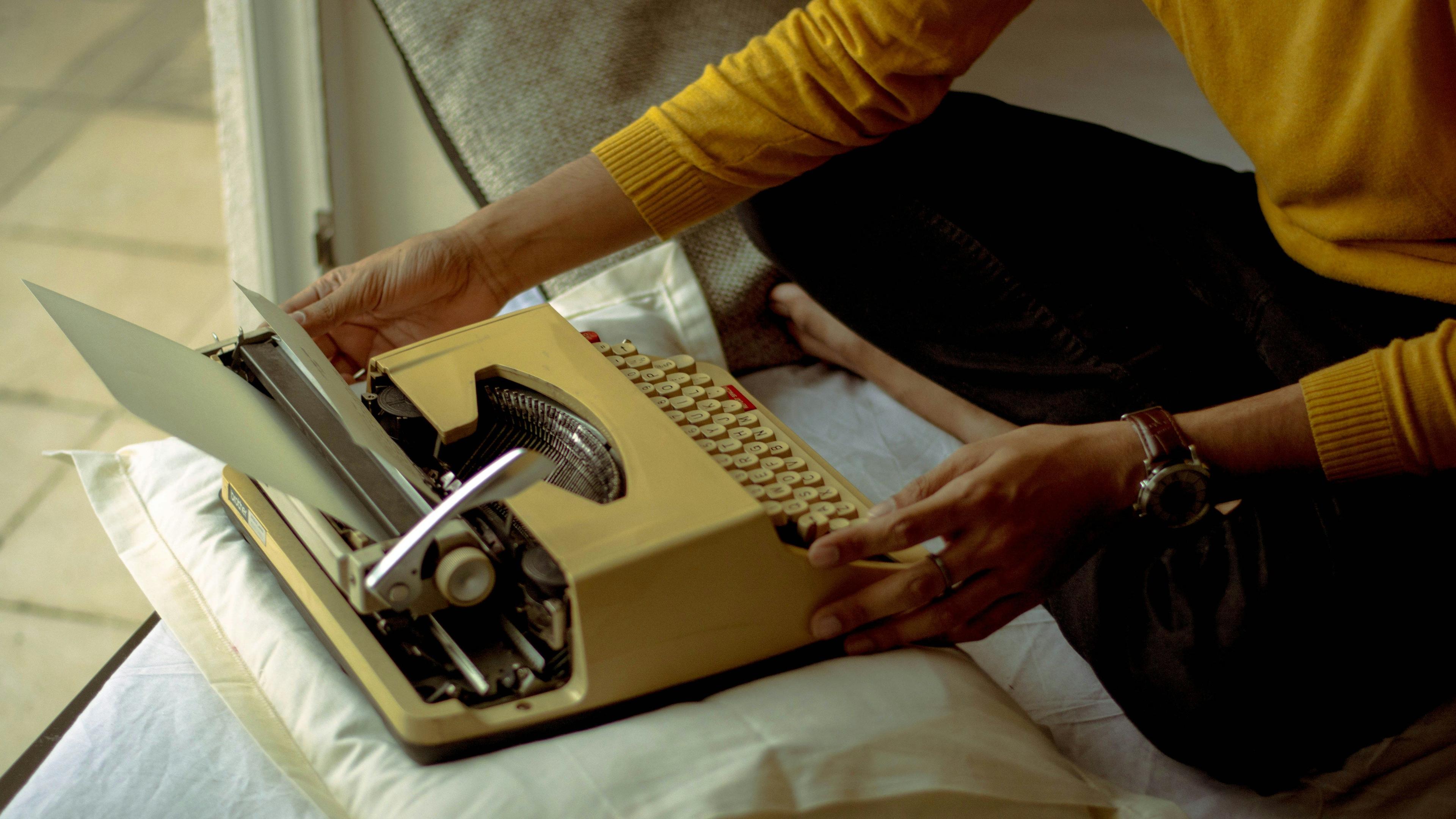 a person is typing on a yellow typewriter