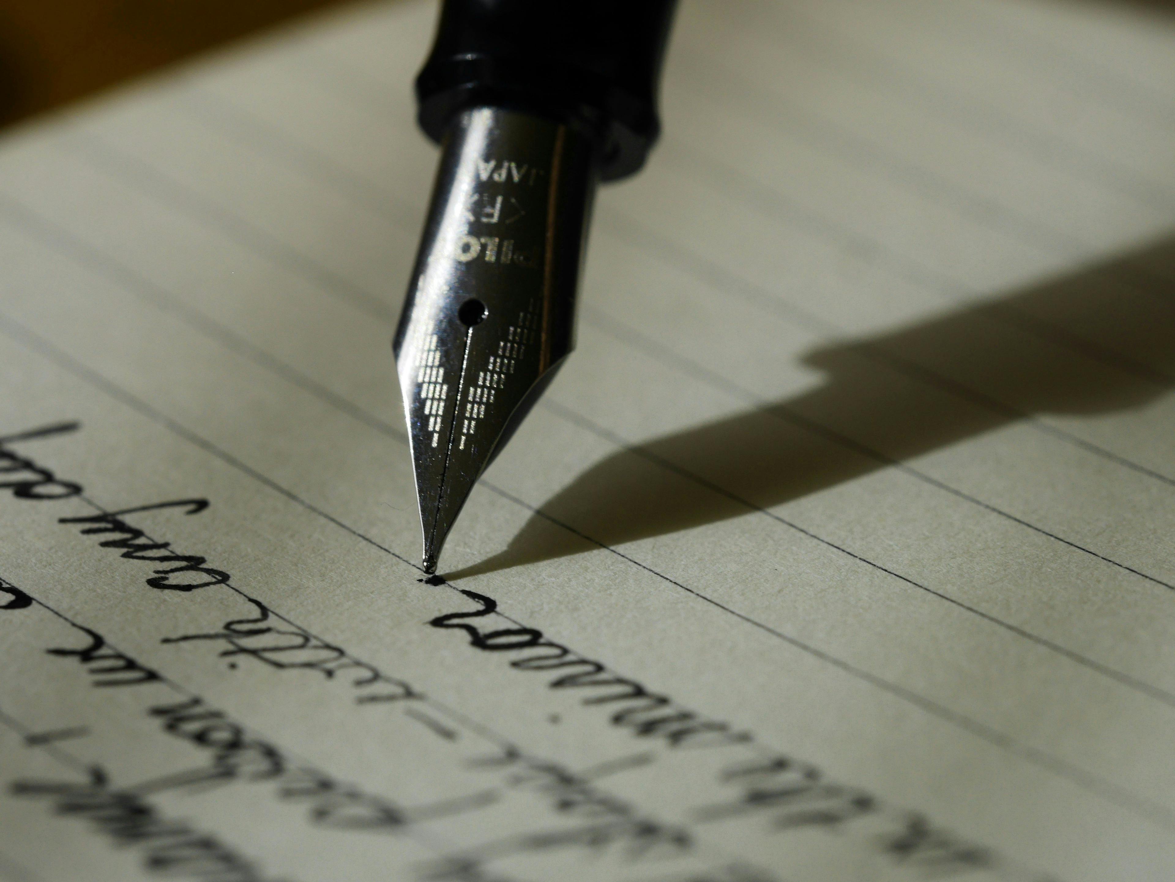 un stylo plume écrit sur une feuille de papier