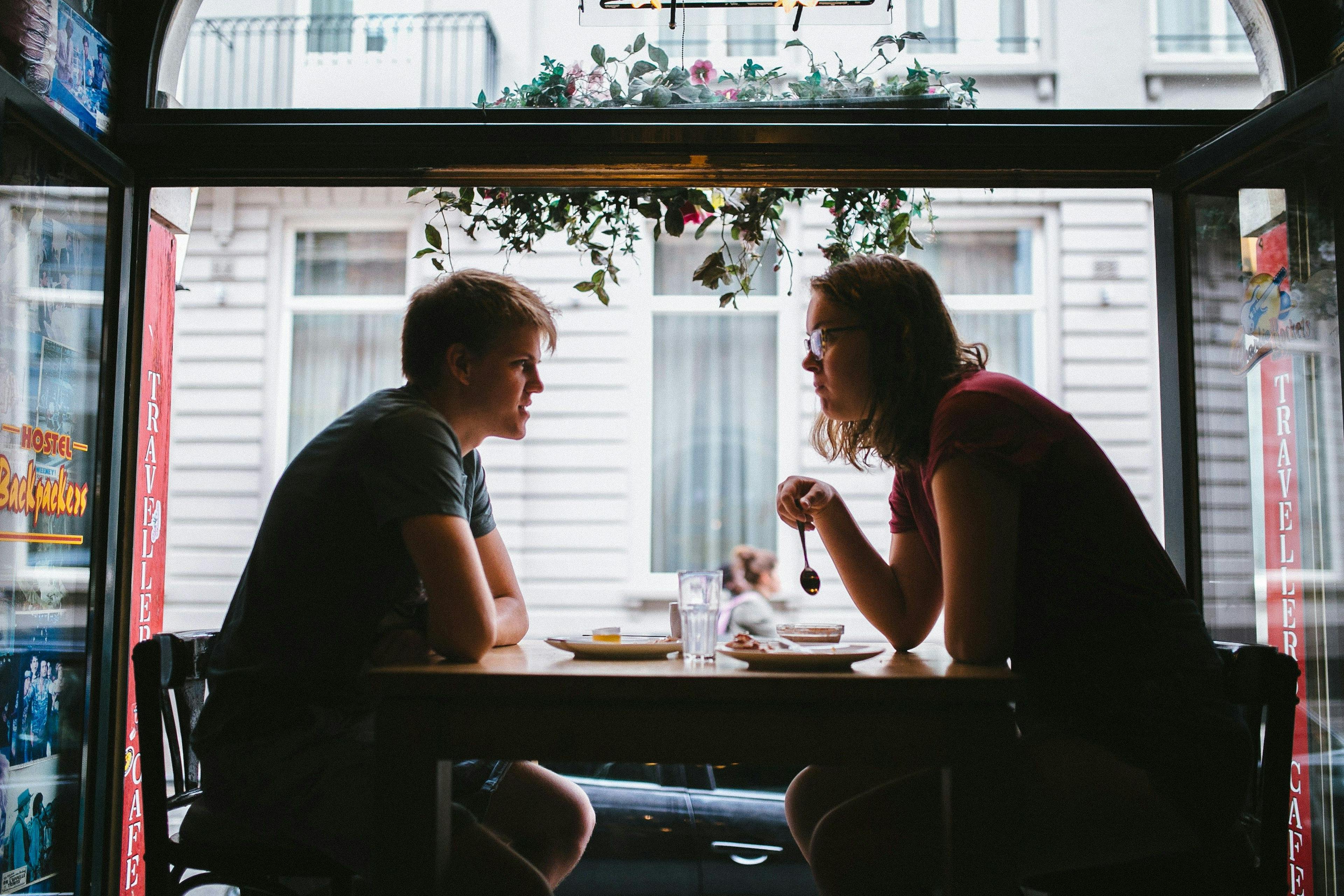 un homme et une femme assis à une table devant une fenêtre
