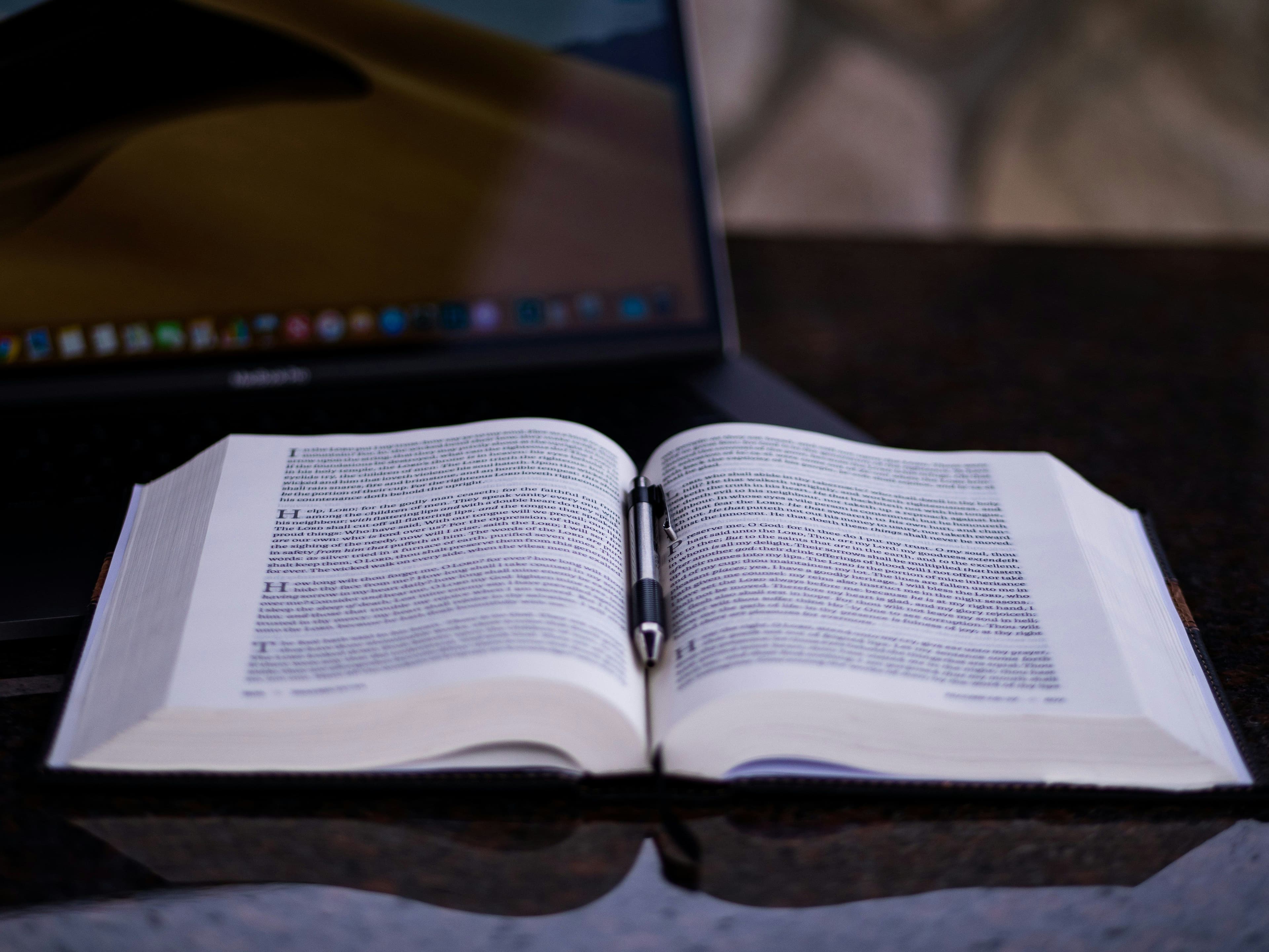 an open book sitting next to a laptop computer